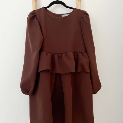 Vestido castanho escuro com folho e mangas bufantes pendurado em cabide