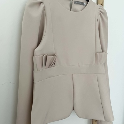 Casaco bege com mangas longas e franzidos junto ao cabide