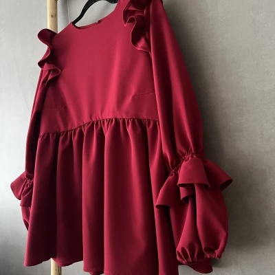 Vestido vermelho escuro com mangas bufantes pendurado numa escada de madeira