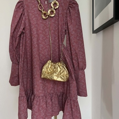 Vestido vermelho floral com folho, colar de elos dourados e mala dourada pequena pendurados