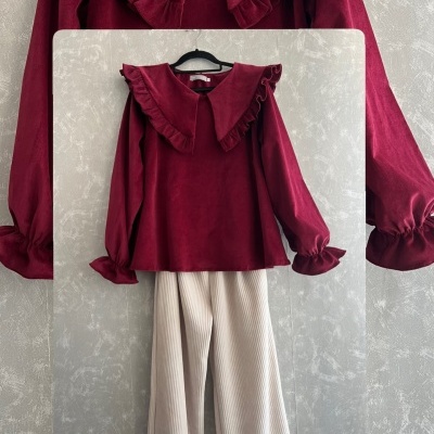 Conjunto blusa bordô e calças brancas pendurado num cabide