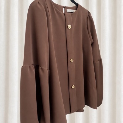 Blusa castanha com botões dourados em cabide preto