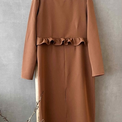 Vestido castanho com folho na cintura pendurado numa escada de madeira