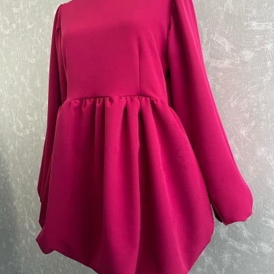 Vestido rosa fúcsia com mangas compridas e saia franzida em manequim.