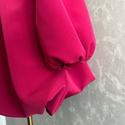 Manga bufante rosa de tecido com punho elástico numa parede cinza texturizada