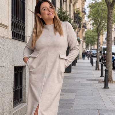 Mulher a usar vestido comprido bege com sapatos vermelhos numa rua urbana.