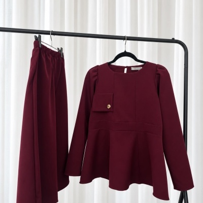 Conjunto bordeaux de mulher com blusa e calças pendurado em suporte preto