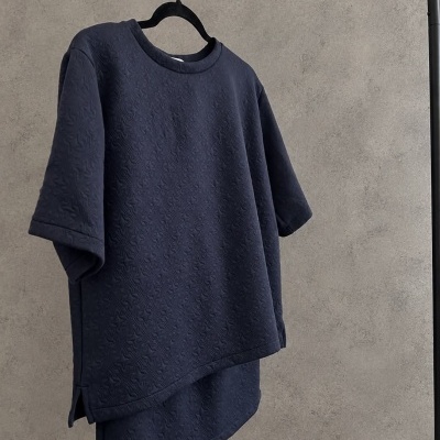 T-shirt azul escuro com padrão texturizado pendurada num cabide preto