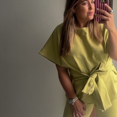 Mulher com blusa amarela e telemóvel com capa de riscas