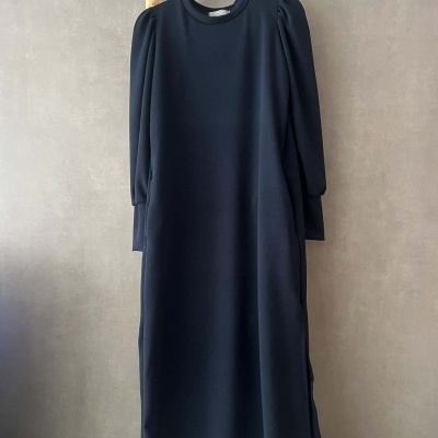 Vestido preto comprido com mangas franzidas pendurado numa estrutura de madeira