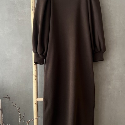 Vestido castanho escuro com mangas compridas e ombros franzidos pendurado num cabide.