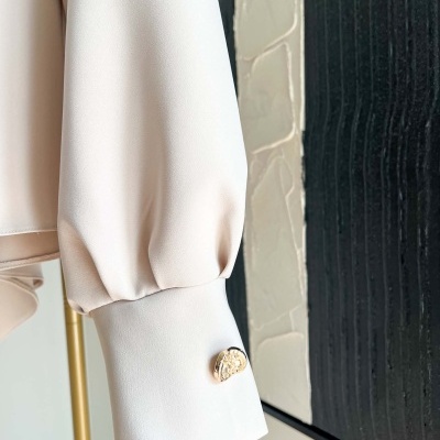 Manga de camisa bege clara com botão dourado