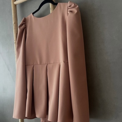 Blusa rosa com mangas bufantes pendurada num cabide