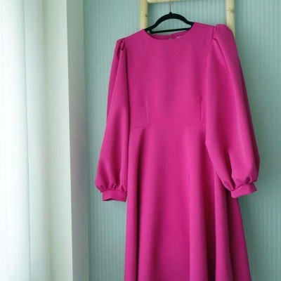 Vestido rosa de manga comprida pendurado numa escada de madeira clara