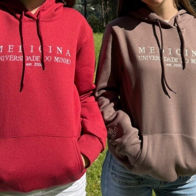 Dois hoodies com capuz e bolso frontal, vermelho e castanho, com texto branco da universidade Medicina.
