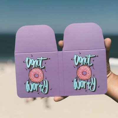 Caixa de cartão roxo com texto 'Donut worry' e desenho de rosquinha