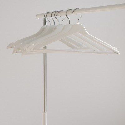 Seis cabides brancos em plástico pendurados em cabideiro metálico prateado