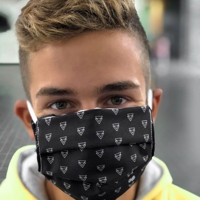 Máscara preta com padrão de triângulos brancos usada por jovem