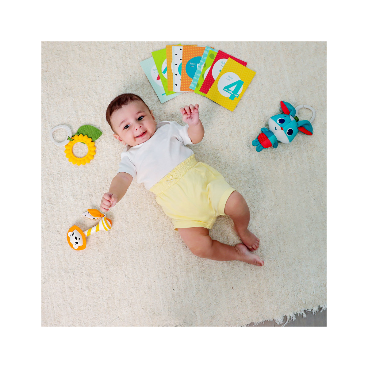 Bebé deitado num tapete com vários brinquedos coloridos à sua volta