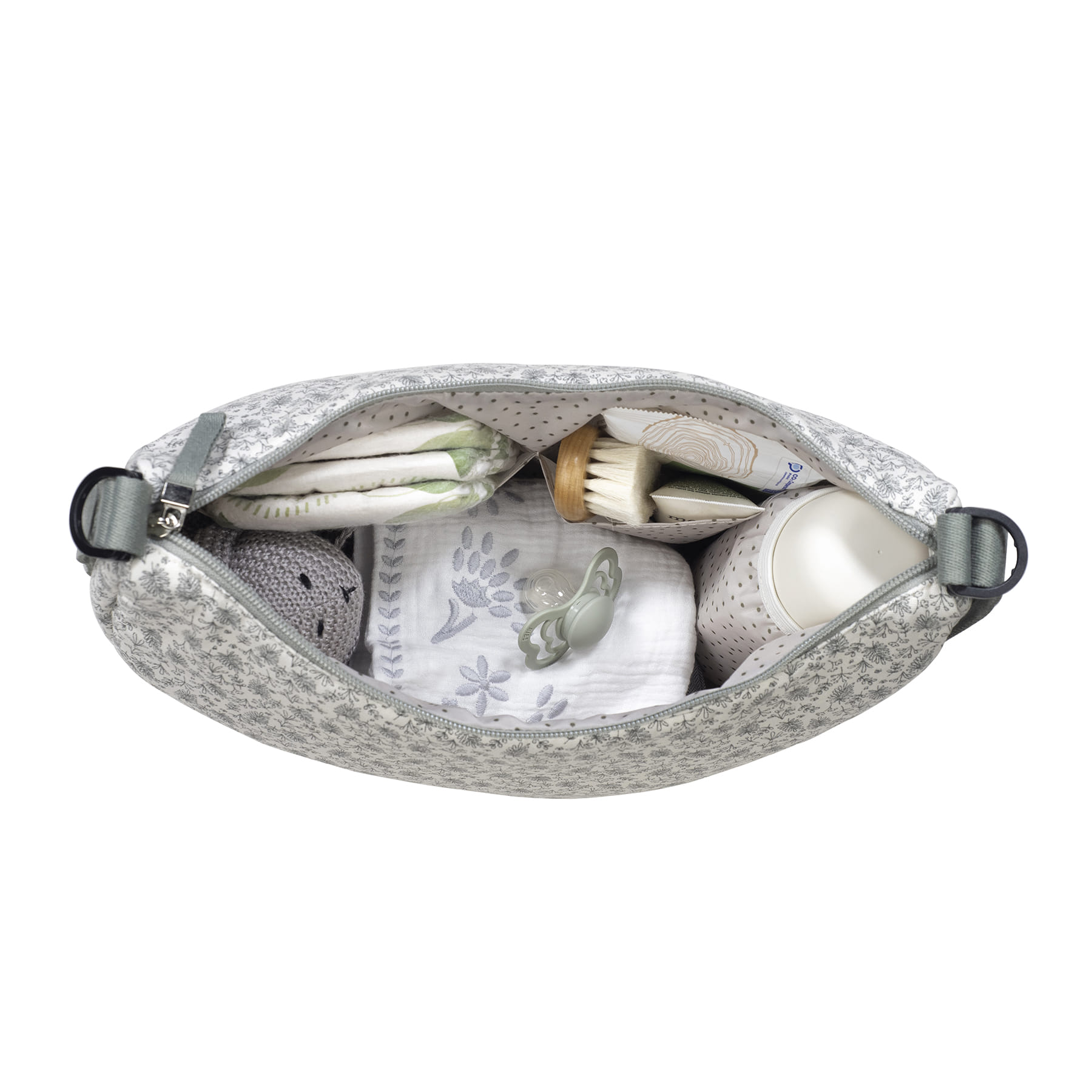 Mala com padrão floral contendo artigos para bebé como fraldas, escova, chupeta e toalha bordada