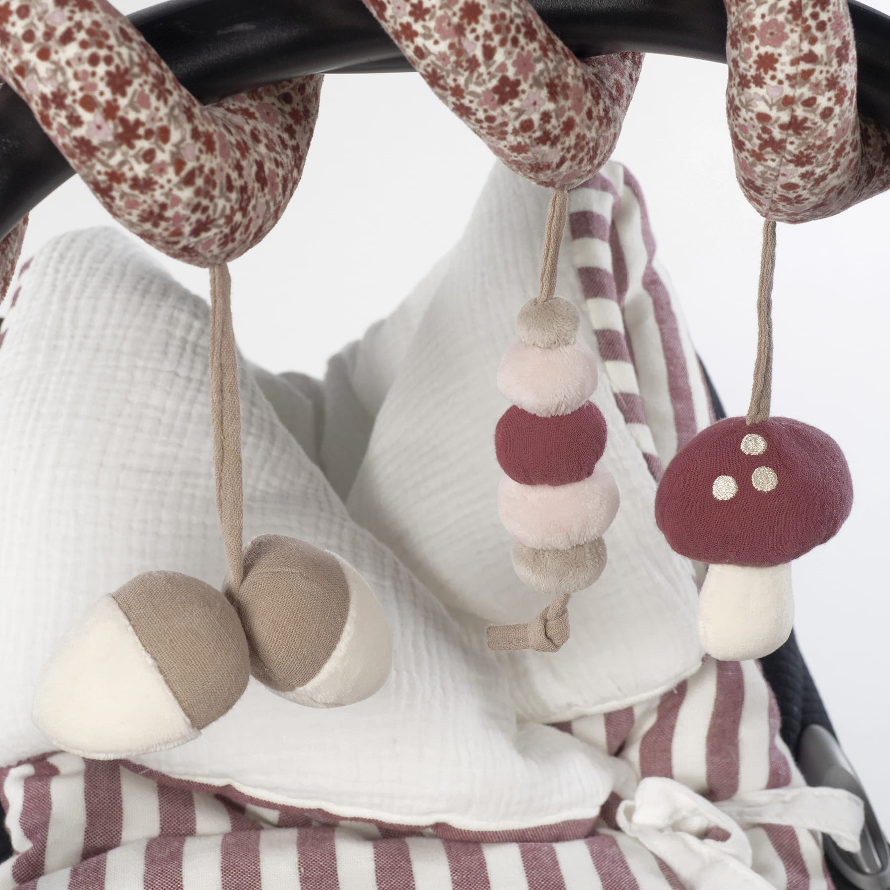 Móbile de tecido colorido pendurado em carrinho com almofadas brancas e riscas bordô