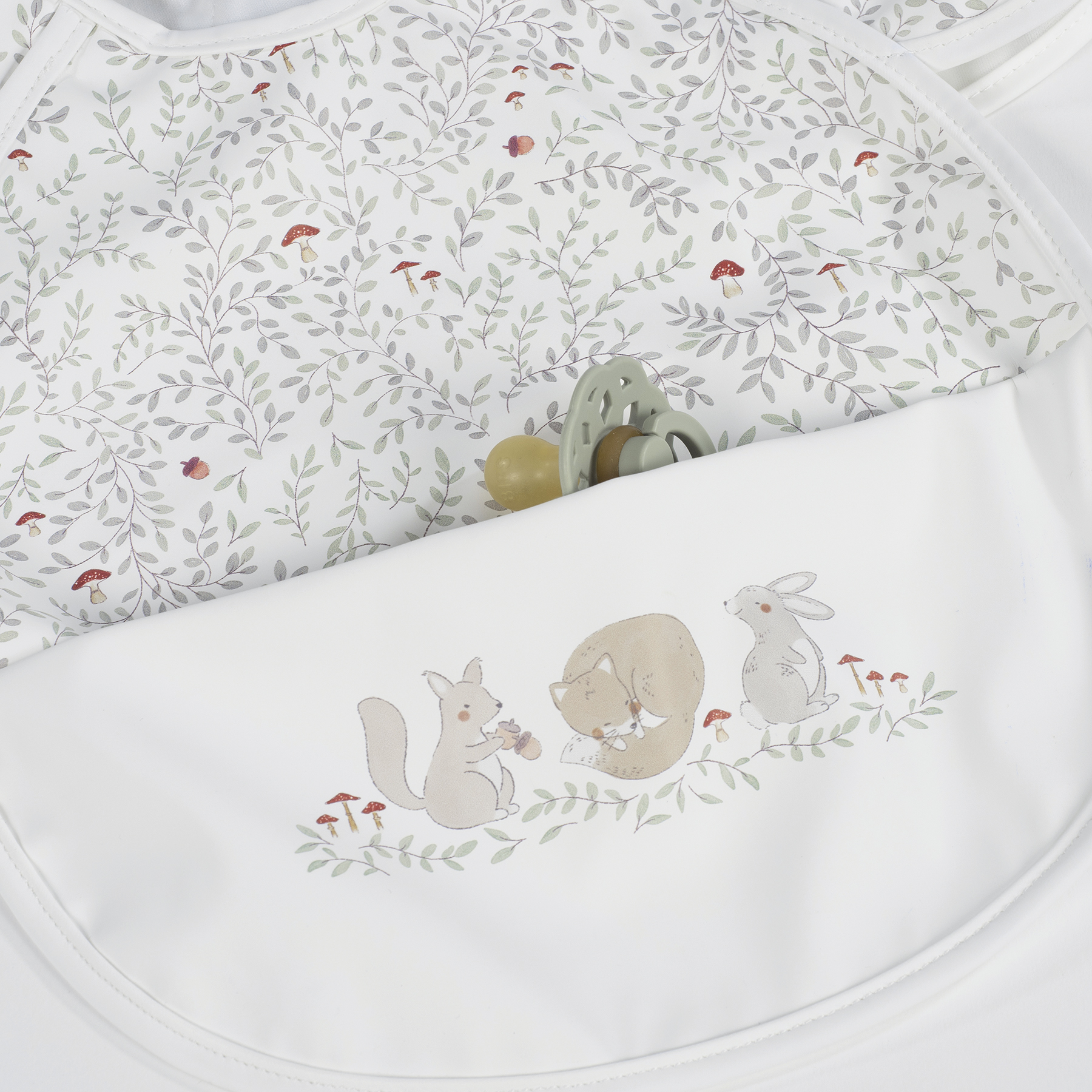 Babete de bebé branco com bolso e ilustrações de animais e folhas
