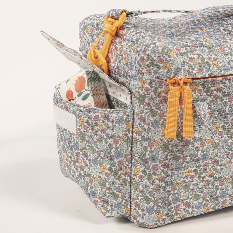 Bolsa floral com zíperes amarelos e bolso lateral com caixa de lenços