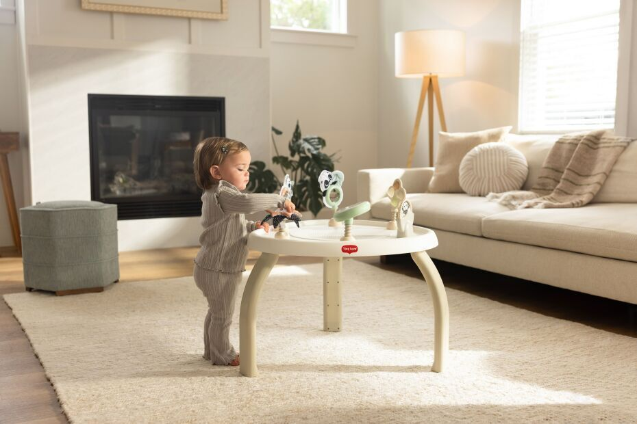 Mesa redonda para criança com brinquedos de animais fixados numa sala de estar clara e acolhedora