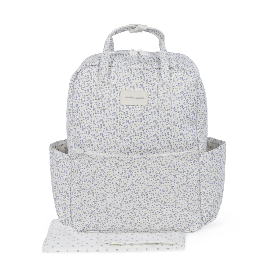 Mochila branca com padrão floral azul e etiqueta pasito a pasito.