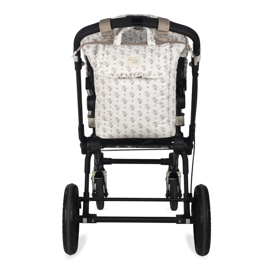 Carrinho de bebé com tecido branco com padrão floral e estrutura preta visto de trás