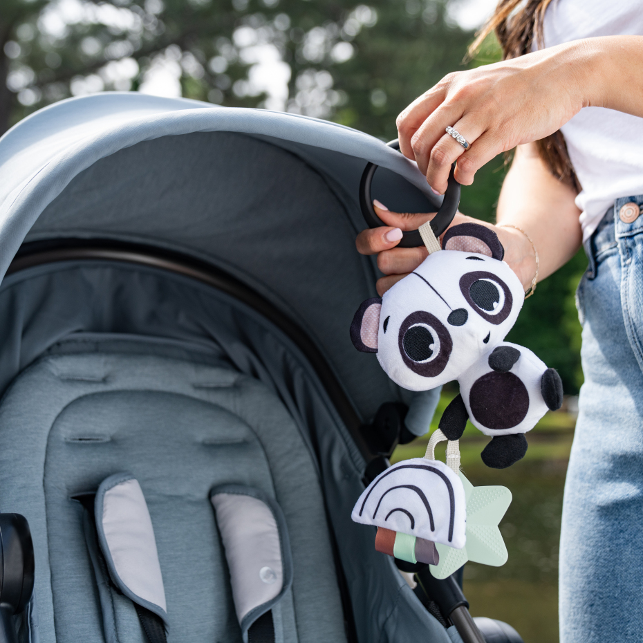 Carrinho de bebé cinzento com brinquedo de peluche panda preto e branco pendurado