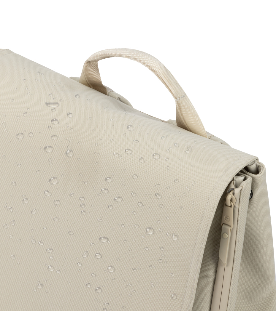 Mochila bege clara com gotas de água na superfície, alça e fecho lateral