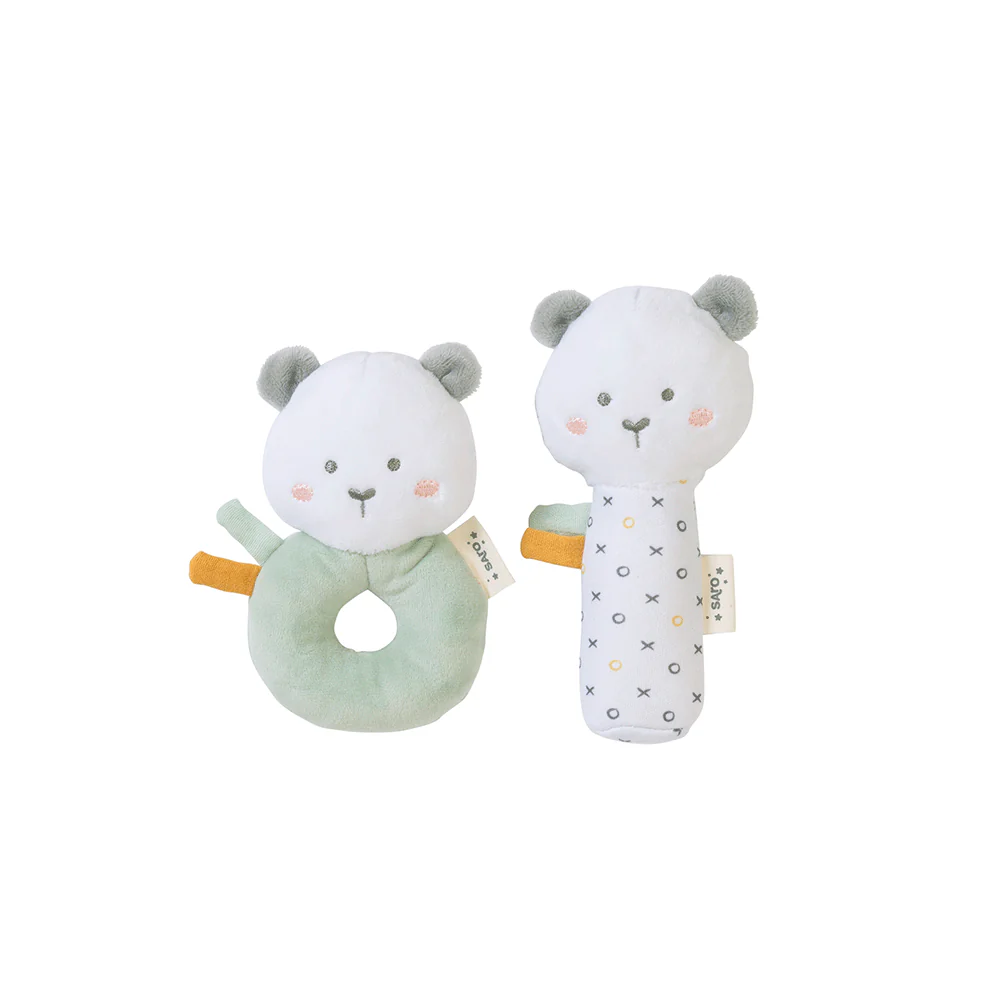 Dois brinquedos de bebé em forma de ursos em tecido macio, um redondo verde claro e outro branco com padrões, ambos com rostos bordados.