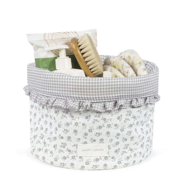 Cesto têxtil com padrão de flores cinzentas e objetos para higiene dentro.