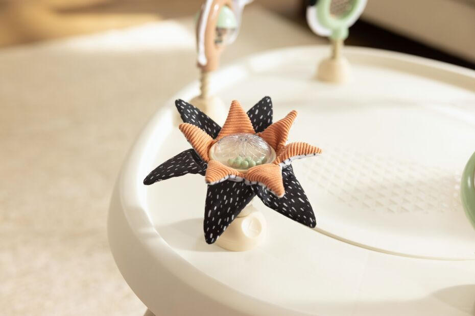 Flor de brinquedo em tecido preto e laranja com centro plástico e pequenas bolas verdes