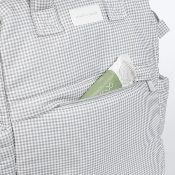 Mochila de tecido cinza e branco com bolso frontal e embalagem verde e branca