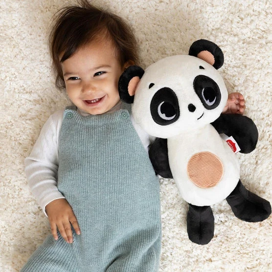 Criança com macacão cinza e camisola branca deitada ao lado de peluche de panda preto, branco e rosa