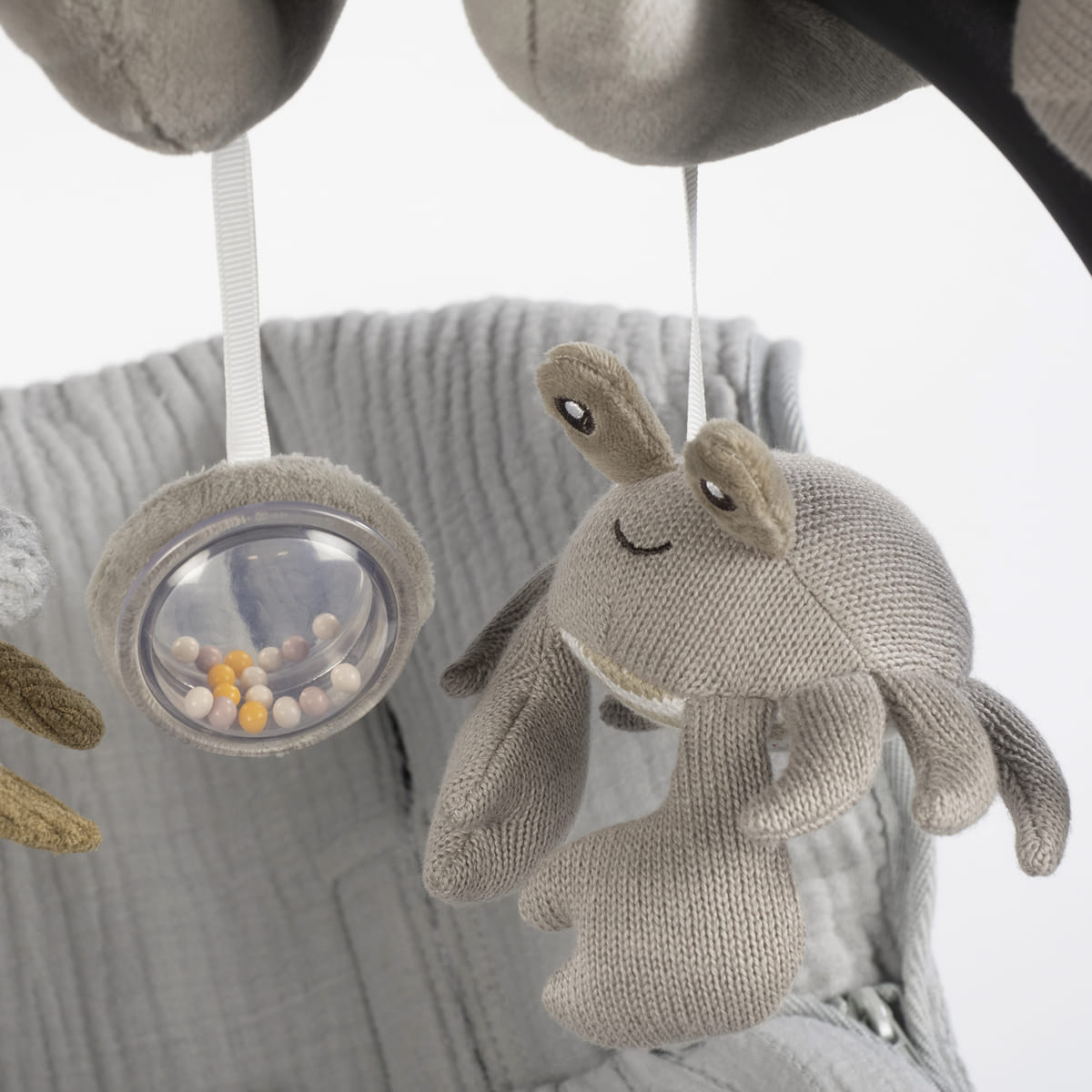Brinquedo pendurado de tecido cinzento com figura de caranguejo e bolas coloridas