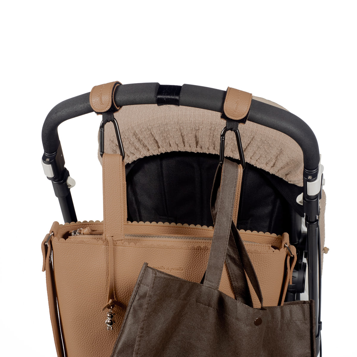 Carrinho de bebé com alça preta e cobertura bege, com duas malas de couro castanhas penduradas