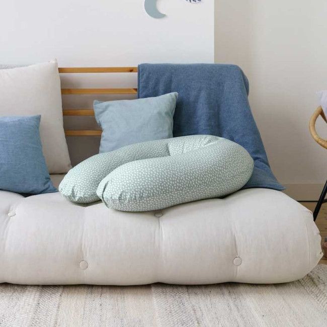 sofá branco com almofadas azuis e almofada de amamentação verde claro com padrão de pontos