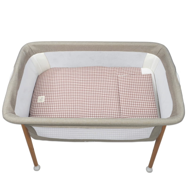 Berço de bebé em tecido bege com colchão xadrez castanho e branco