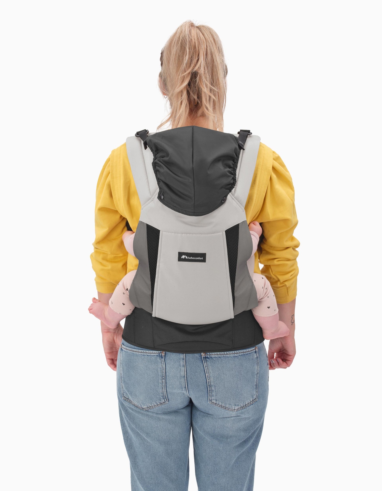 Mochila porta-bebé cinzenta e preta usada por mulher com bebé