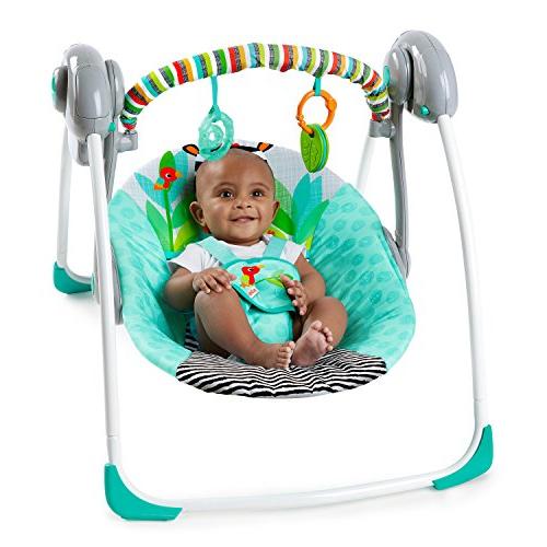 Bebé sentado numa balança azul turquesa com barra colorida e brinquedos pendurados