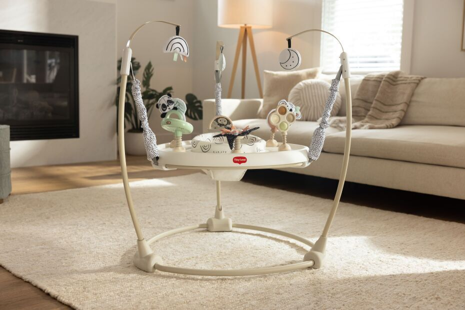 Cadeirinha de brincar para bebé com brinquedos pendurados numa sala clara