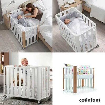 berço-cama branco com detalhes em madeira natural, rodízios e roupa de cama branca com almofadas coloridas