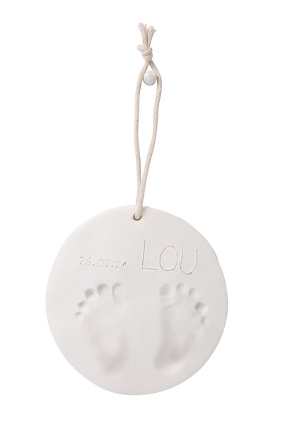 Disco branco com pezinhos em relevo, cordão pendurado e texto gravado