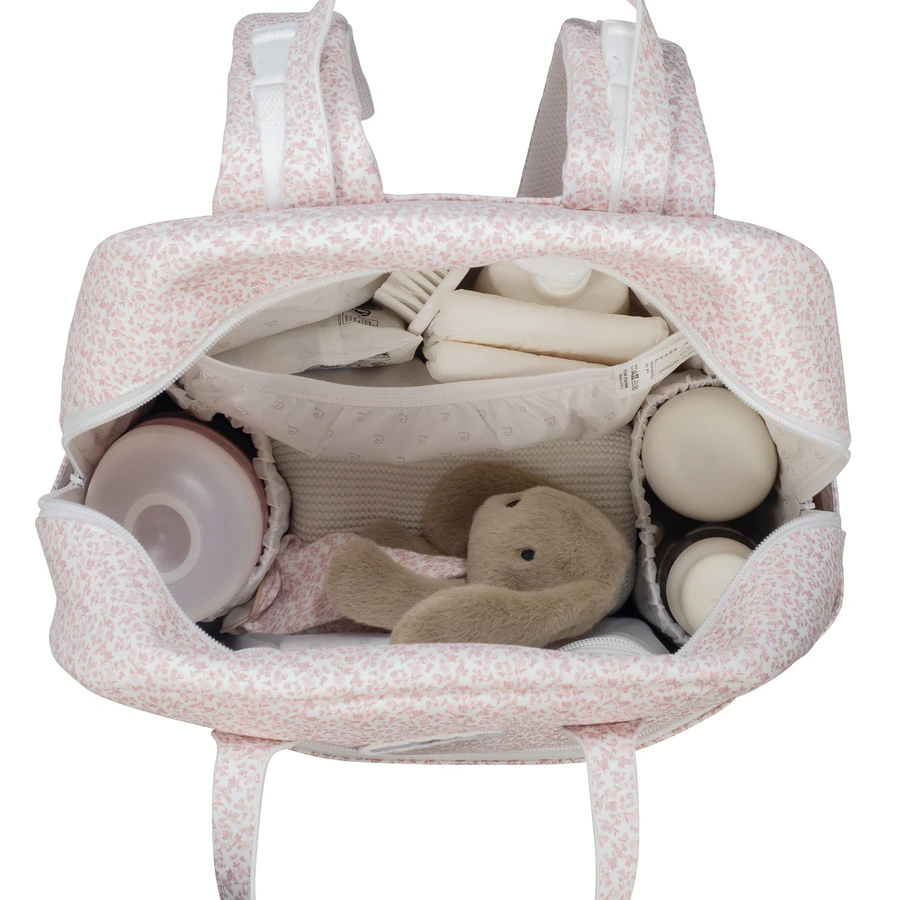 Interior de mochila rosa clara com padrão floral e itens para bebé