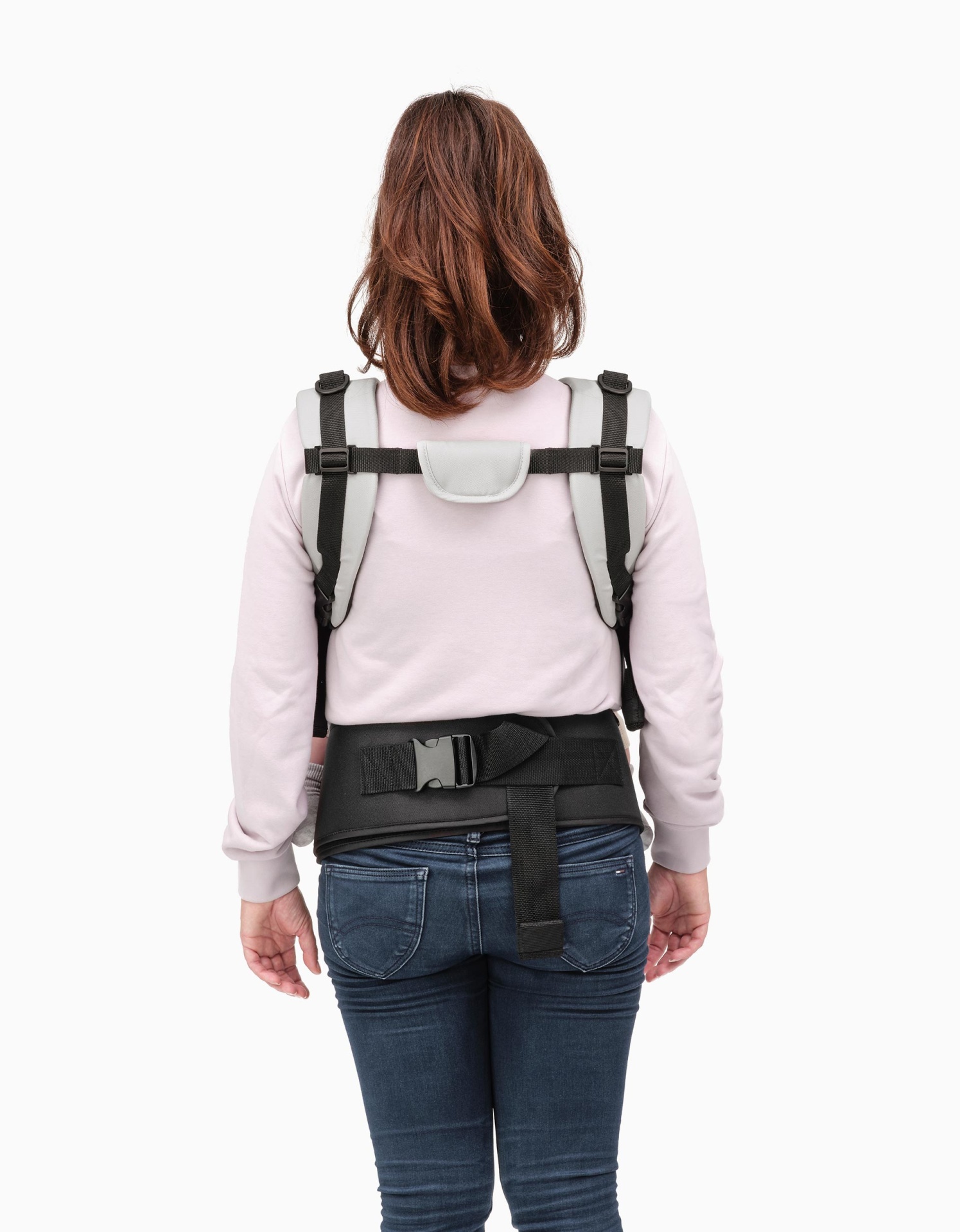 Pessoa a usar arnês de segurança preto com suporte lombar sobre camisola rosa e jeans
