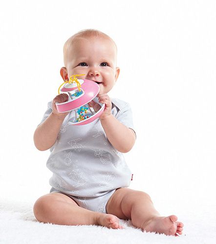 Bebé sentado com body cinzento claro a brincar com brinquedo rosa e amarelo