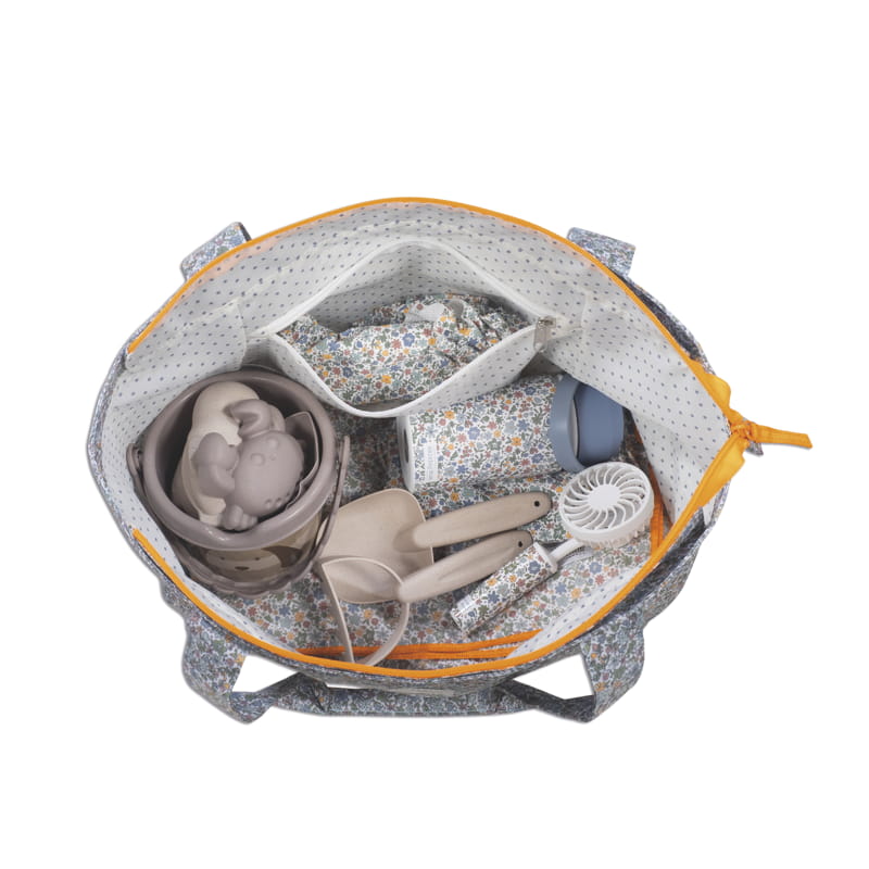 Bolsa floral aberta contendo itens de praia e acessórios variados